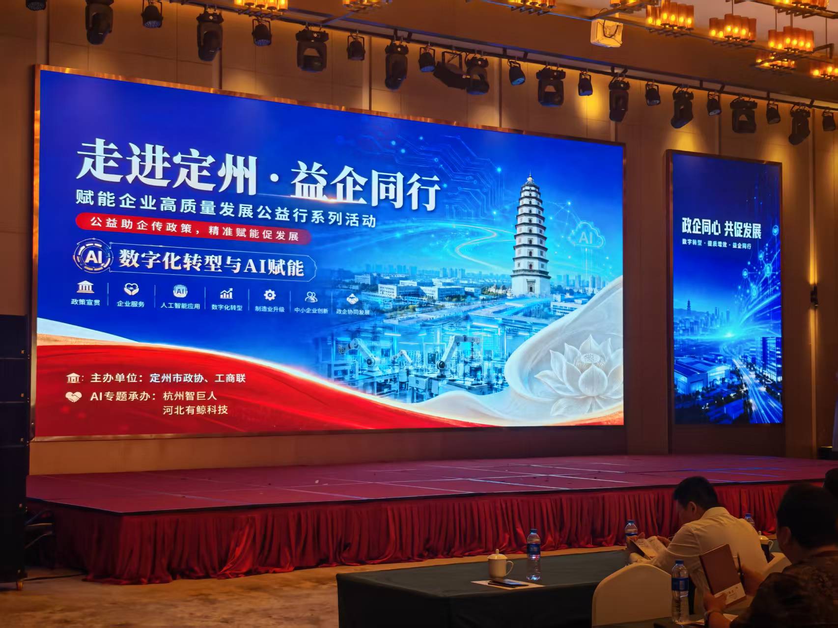 走进定州·益企同行活动现场：主屏显示AI数字化转型与AI赋能专题，AI专题承办单位为杭州智巨人、河北有鲸科技